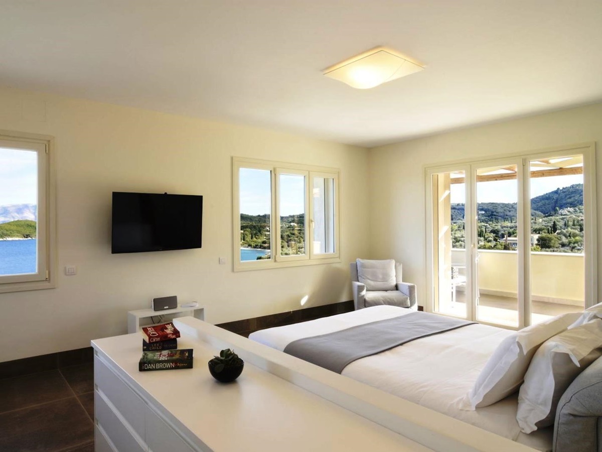 Double bedroom with white furniture and patio doors onto sun terrace at villa eleni in corfu, Greece