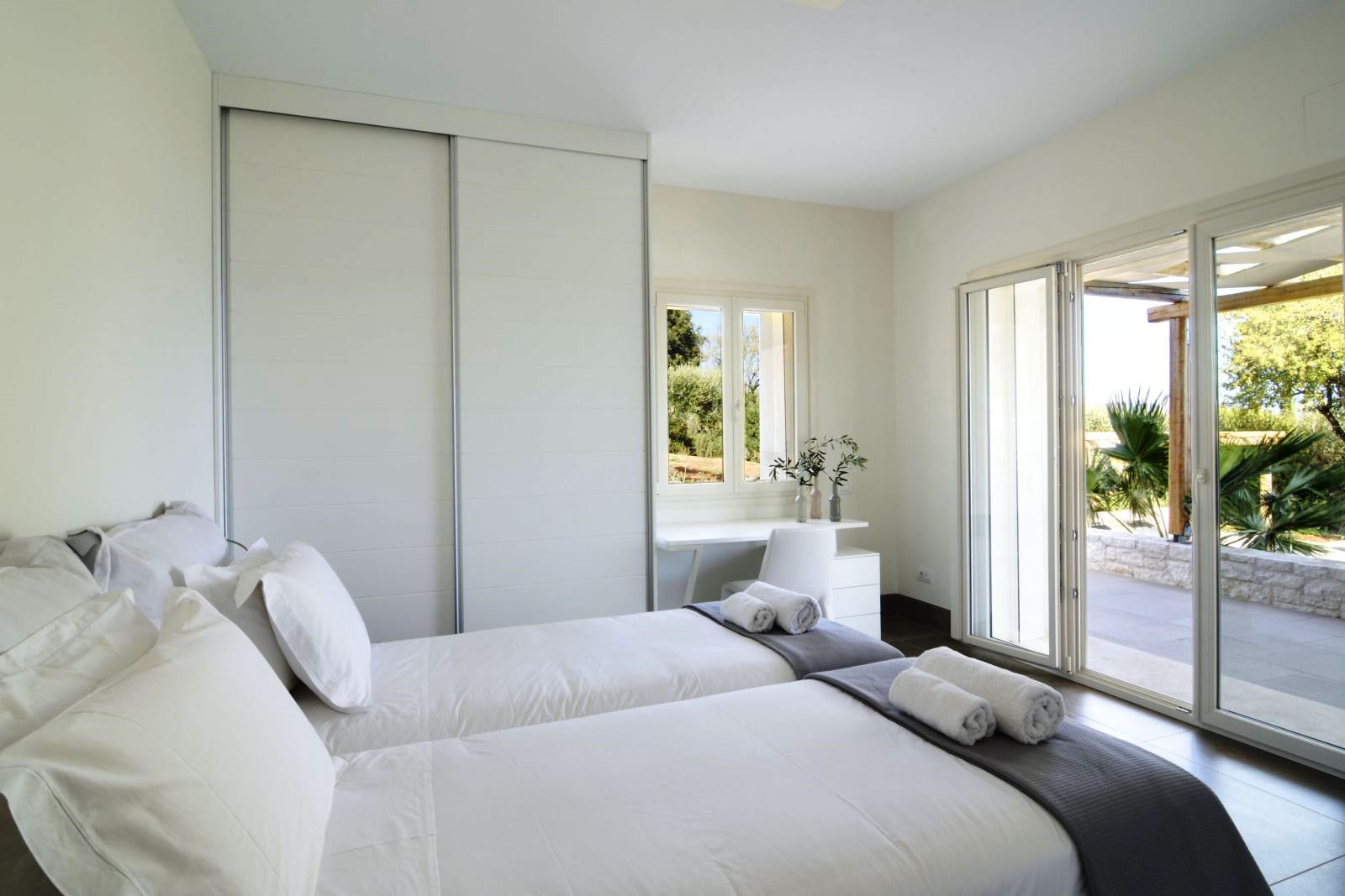 Twin bedroom with patio doors and black out blinds over the windows at villa eleni in corfu, Greece