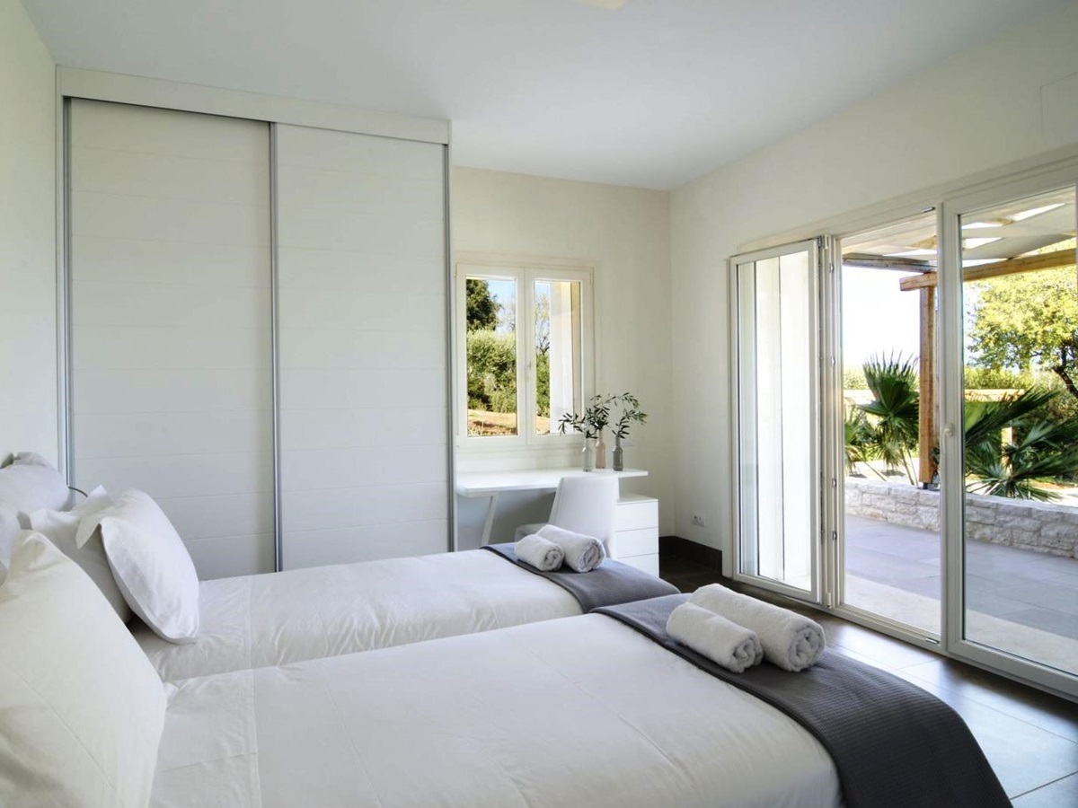Twin bedroom with patio doors and black out blinds over the windows at villa eleni in corfu, Greece