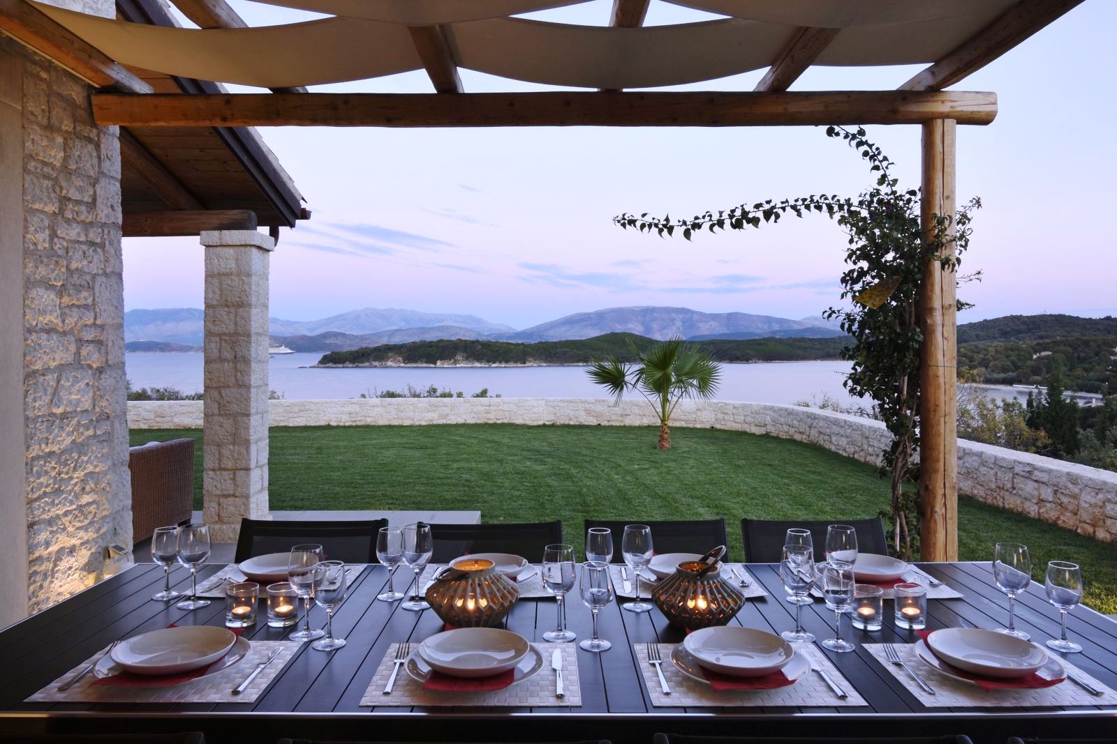 Dining table set for dinner on an outdoor terrace overlooking the sea at villa eleni in corfu, Greece