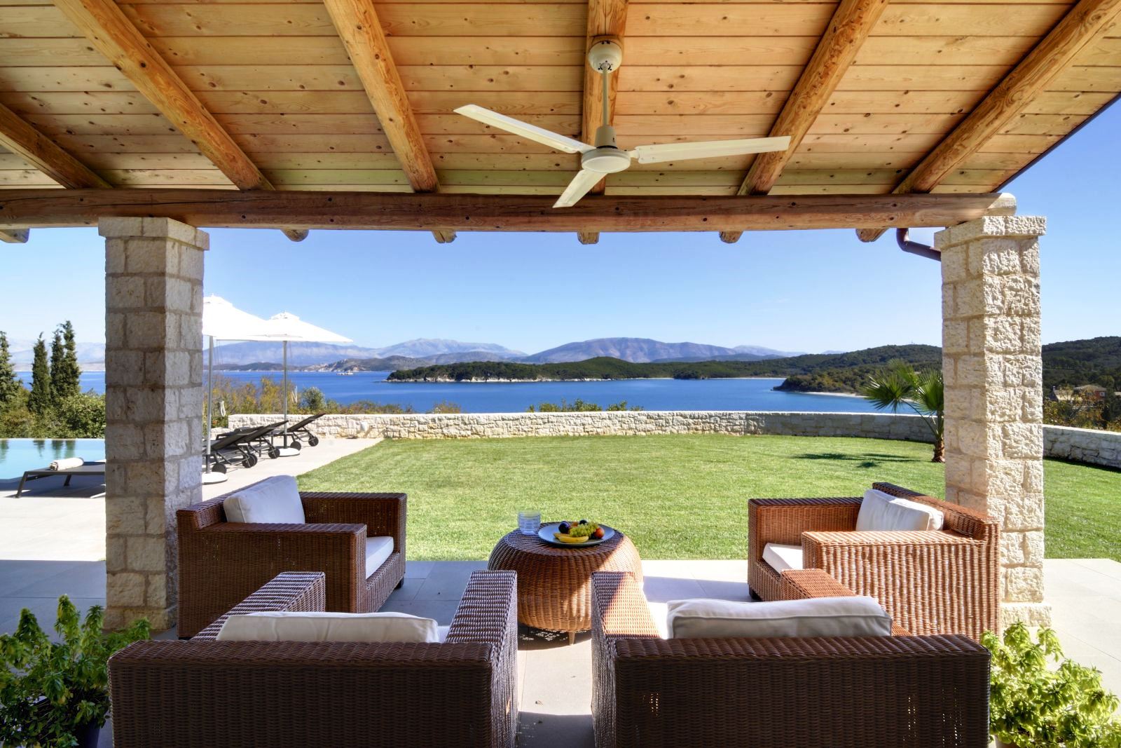 4 comfy wicker chairs with white cushions under a wooden roof with ceiling fan at villa eleni in corfu, Greece