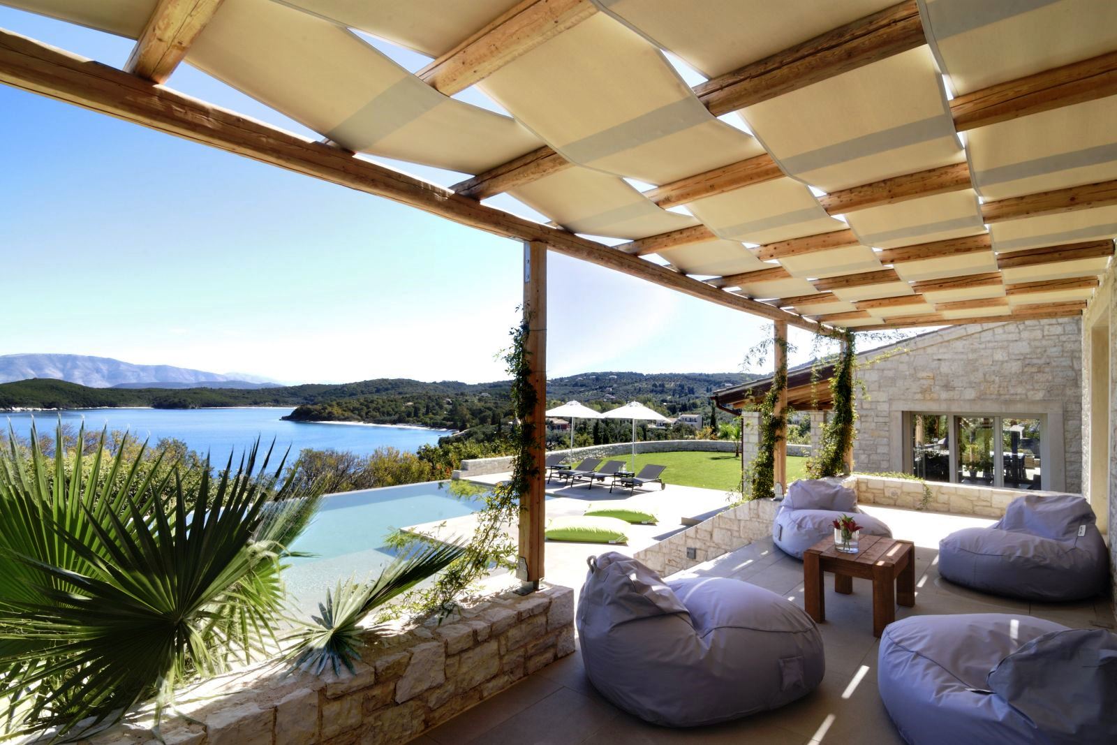 4 white beanbag chairs and small table on a shaded terrace overlooking the pool at villa eleni in corfu, Greece