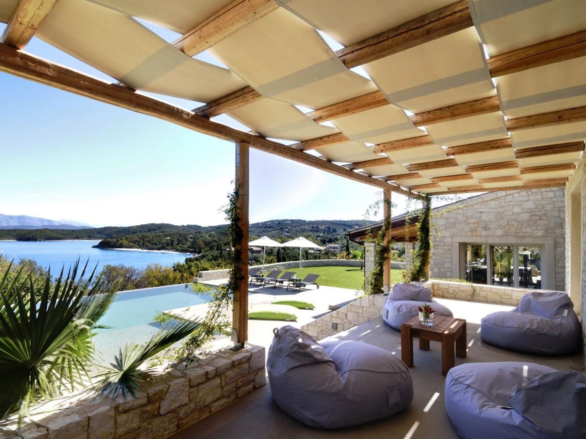 4 white beanbag chairs and small table on a shaded terrace overlooking the pool at villa eleni in corfu, Greece