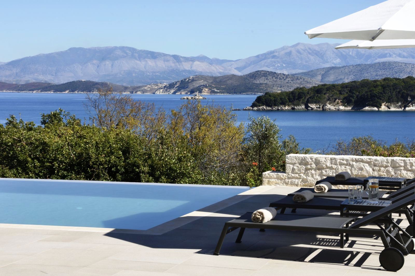 View over the pool with the sea and hills in the background at villa eleni in corfu, Greece