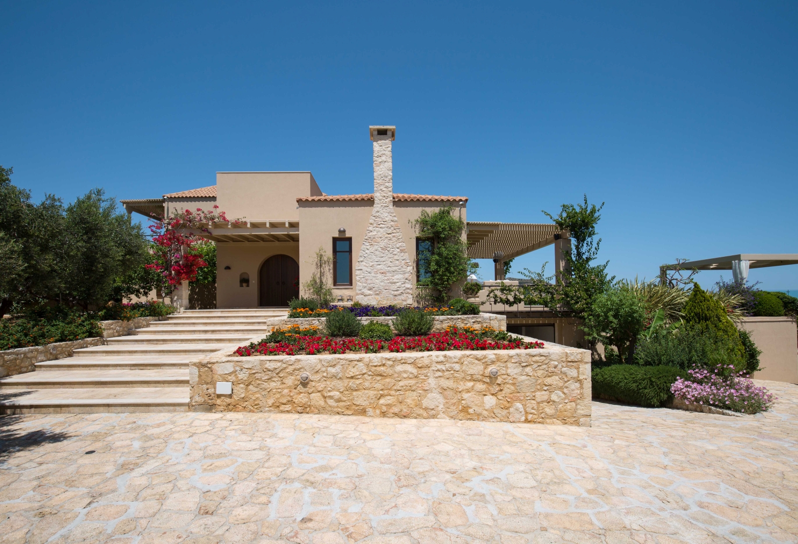 Flowers, trees, plants, driveway, entrance steps and front door at Villa Filira on Crete, Greece 