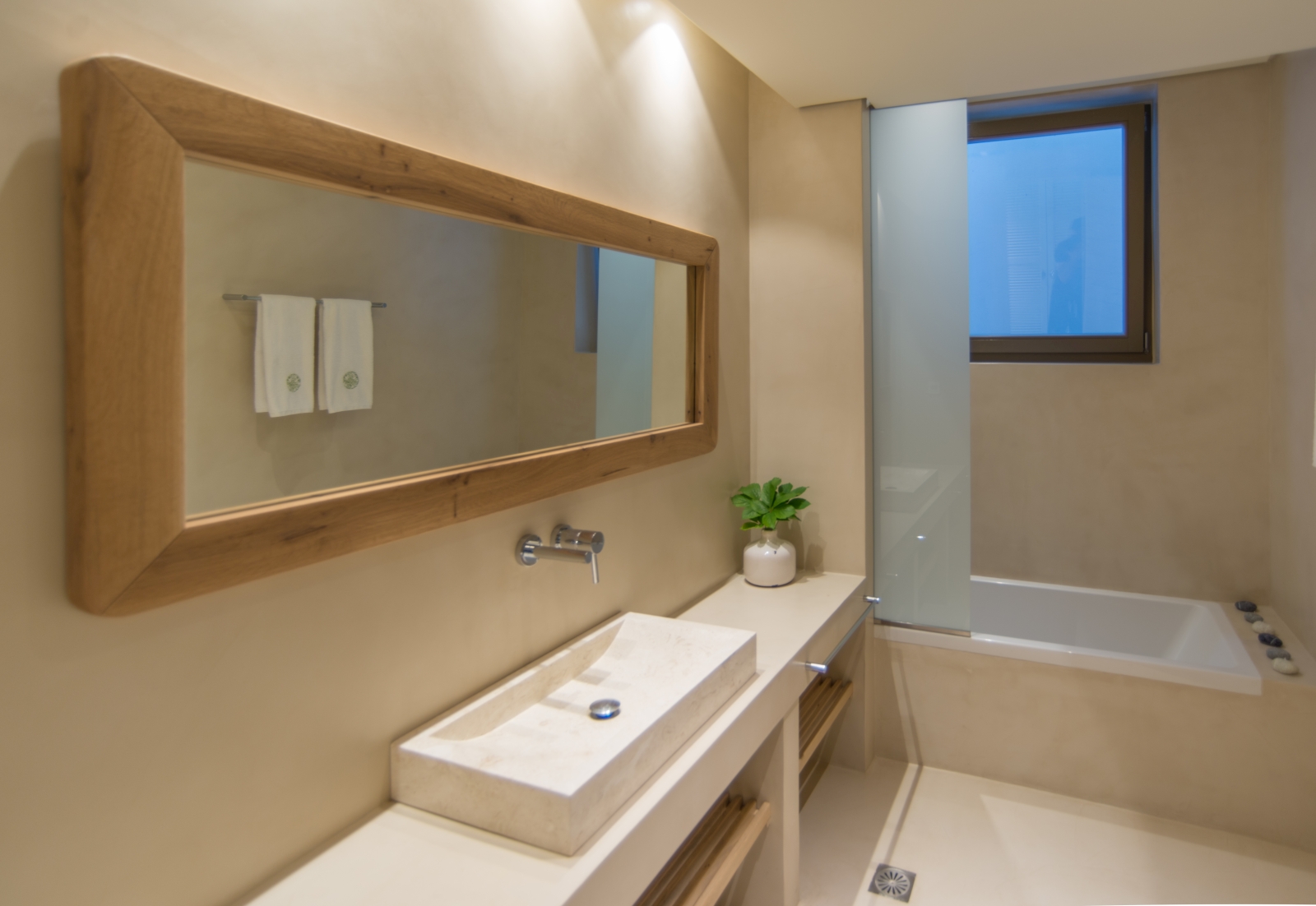 Bathroom with sink, long mirror, towel rail, plant, bath and window at Villa Ianira on Crete, Greece
