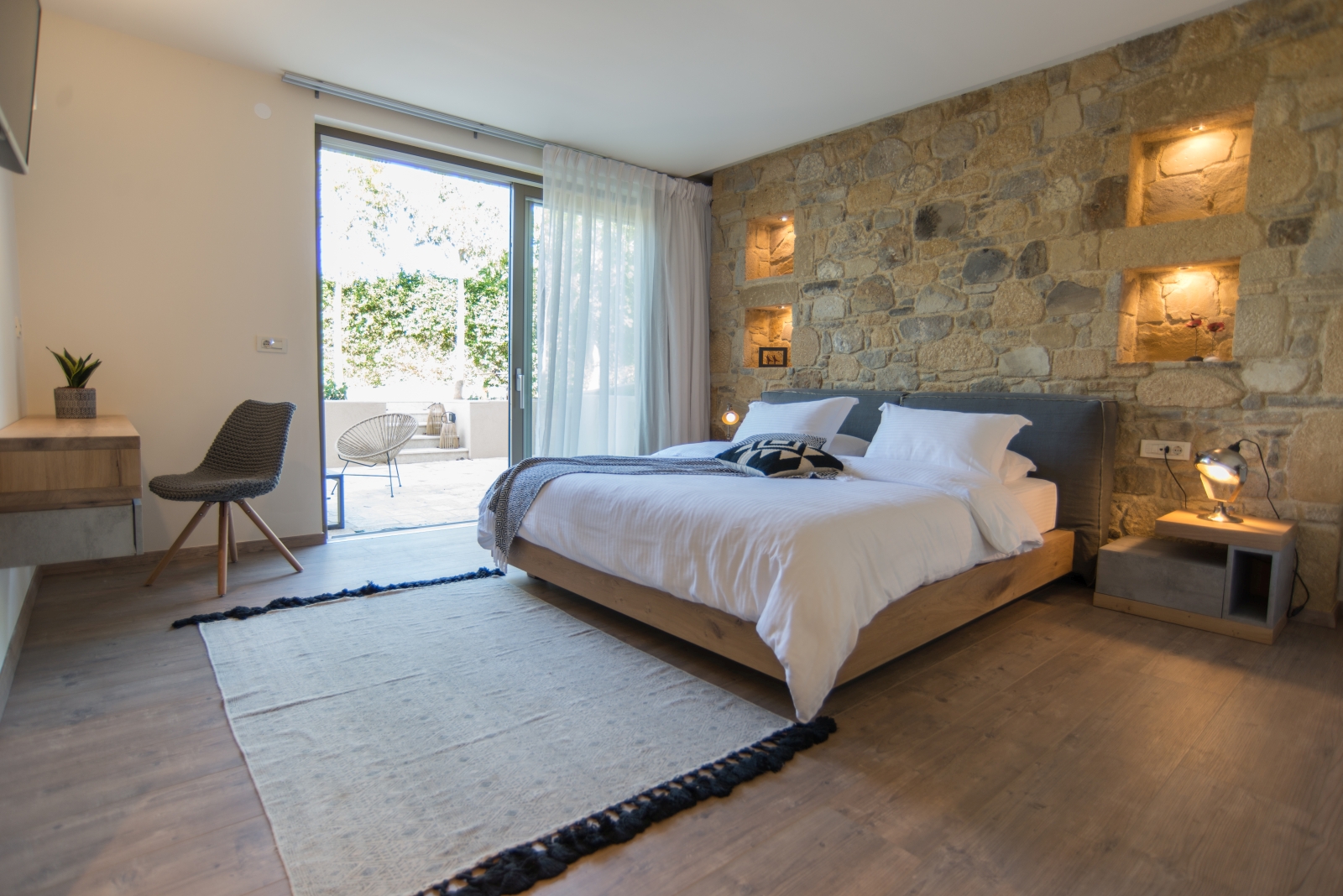 Bedroom with double bed, beside table, lamp, rug, desk, plant, armchair and patio doors at Villa Ianira on Crete, Greece