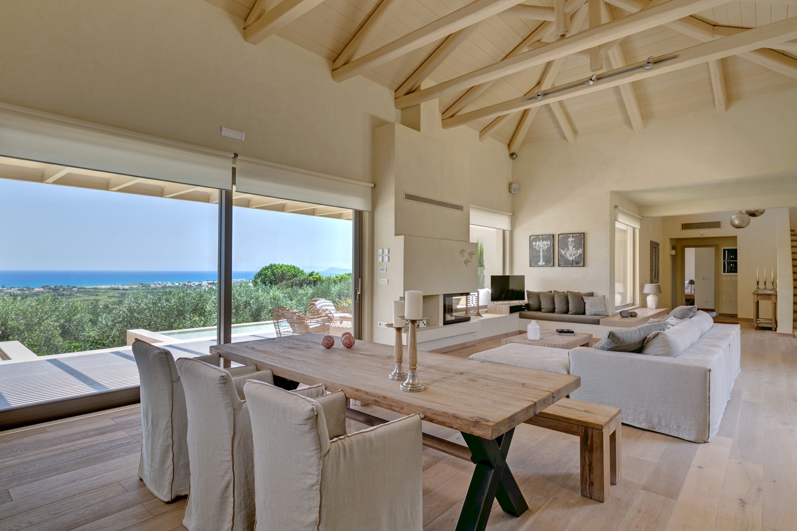 Living area with table, comfy chairs, bench, candles, sofa and patio doors with sea view at Villa Ianira on Crete, Greece