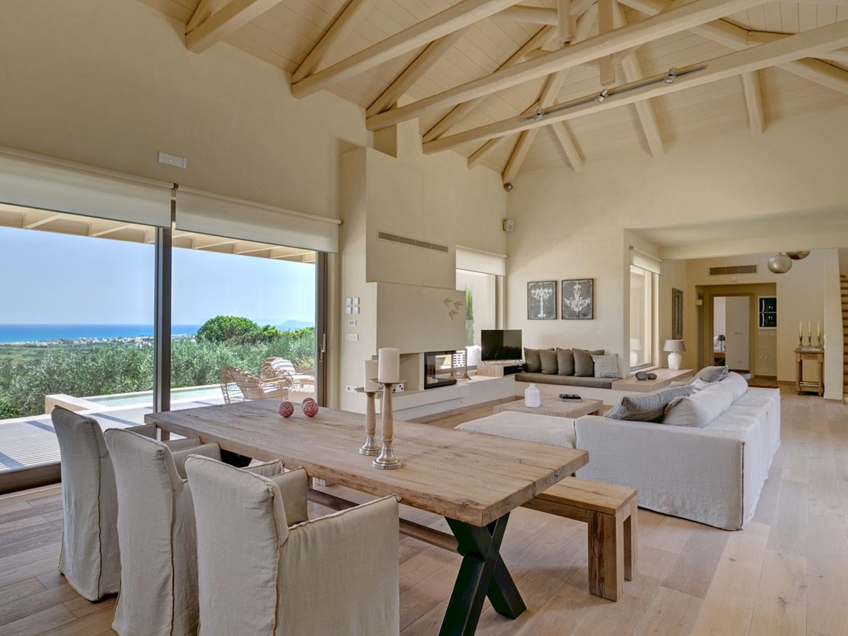 Living area with table, comfy chairs, bench, candles, sofa and patio doors with sea view at Villa Ianira on Crete, Greece