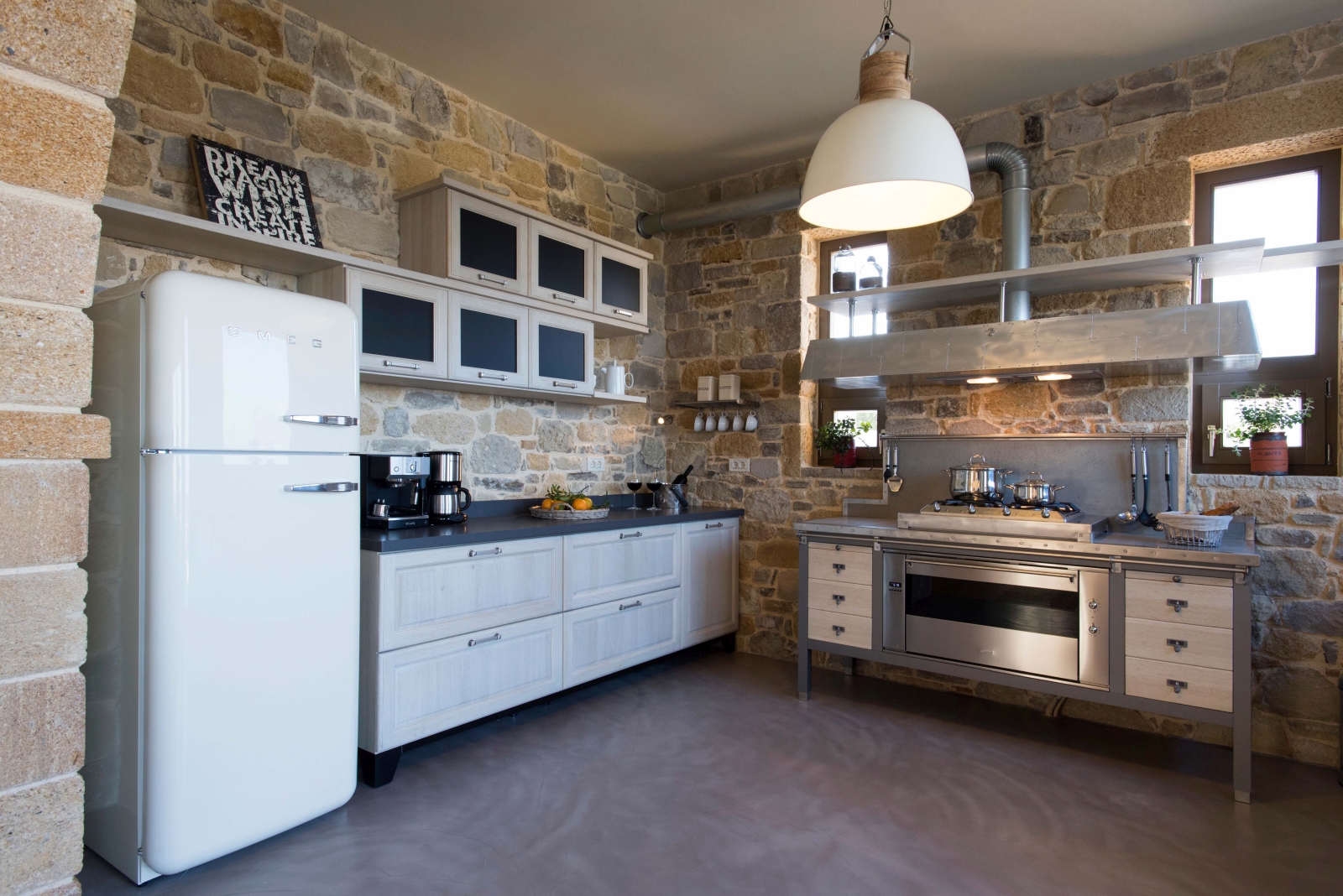 Kitchen with stone walls, overhanging light, cupboards, SMEG fridge and other appliances at Villa Ianira on Crete, Greece