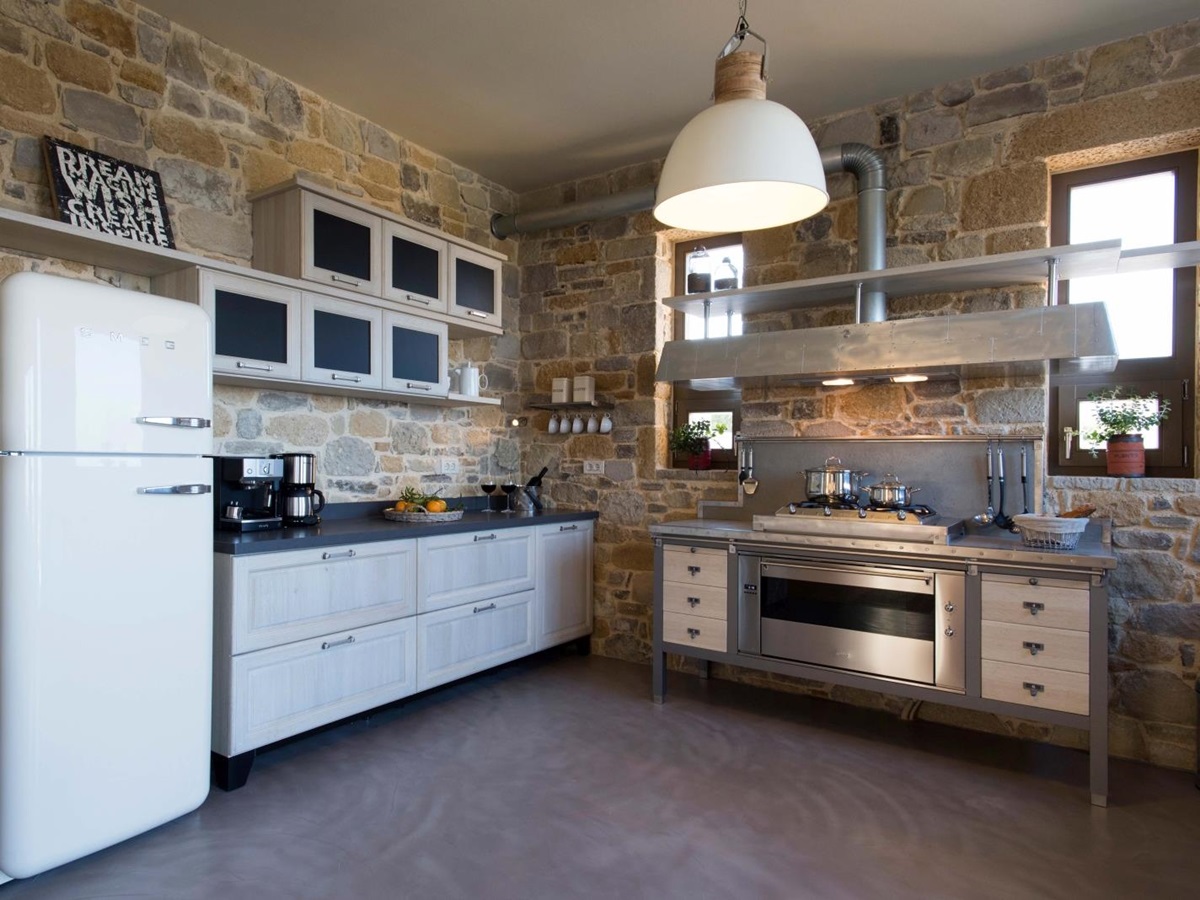 Kitchen with stone walls, overhanging light, cupboards, SMEG fridge and other appliances at Villa Ianira on Crete, Greece