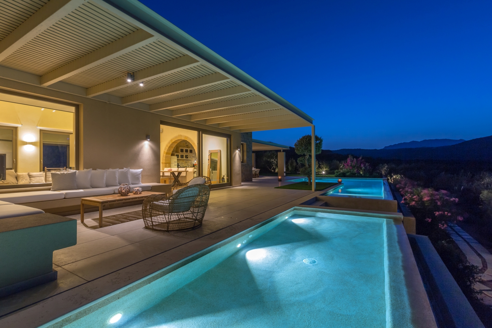 Pool and covered outdoor lounge area with sofas, comfy chairs, coffee table and patio doors at Villa Ianira on Crete, Greece