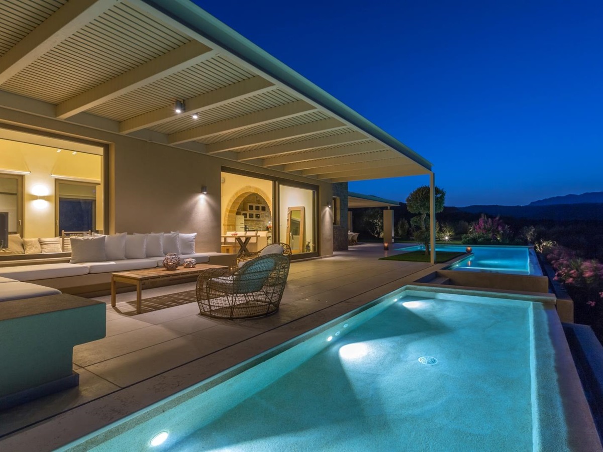 Pool and covered outdoor lounge area with sofas, comfy chairs, coffee table and patio doors at Villa Ianira on Crete, Greece