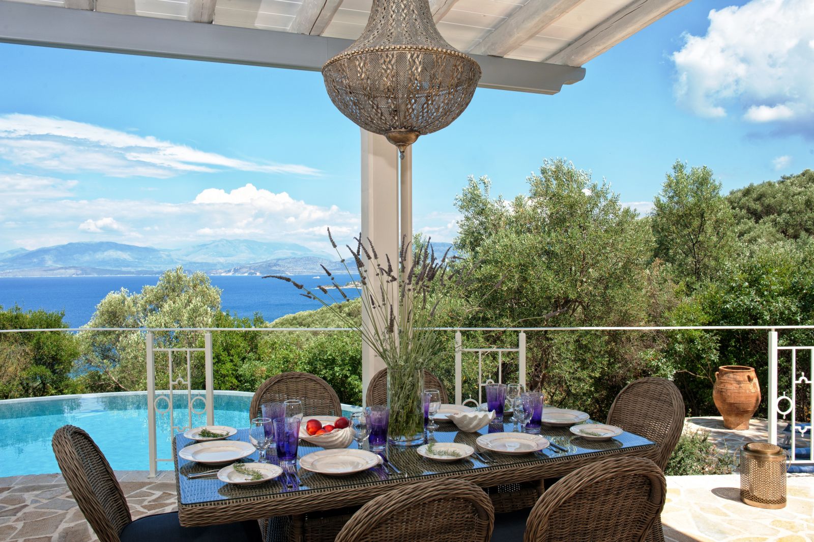 Brown wicker dining table set for dinner and six chairs on the terrace with view of the sea villa kalamaki in corfu, Greece