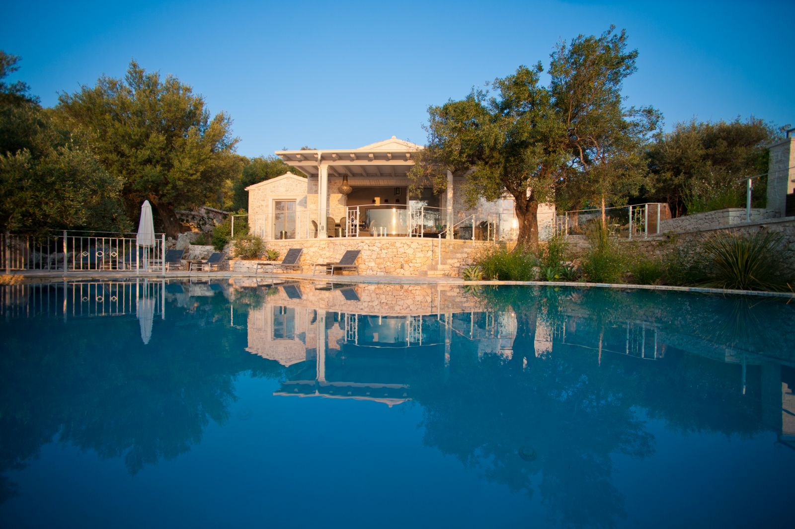 View over the blue pool up to the stone terrace at villa kalamaki in corfu, Greece