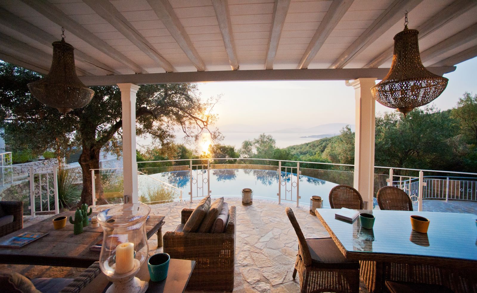 Covered outdoor terrace with two tables and chairs overlooking the pool at villa kalamaki in corfu, Greece
