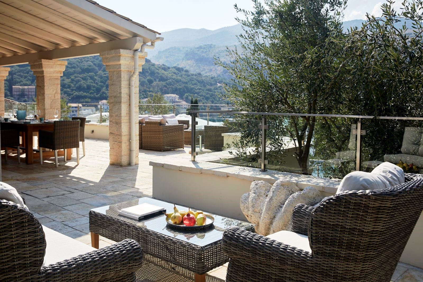 two wicker chairs and a table on the outdoor terrace at villa castro on Corfu