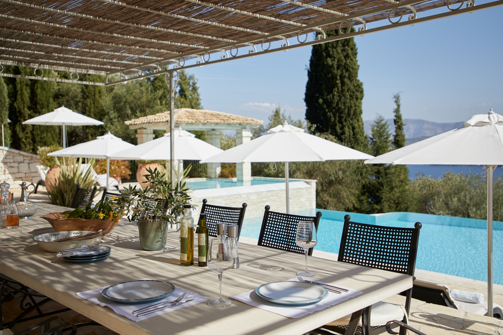 Outdoor shaded dining with pool in background at Villa Kerasia in Corfu