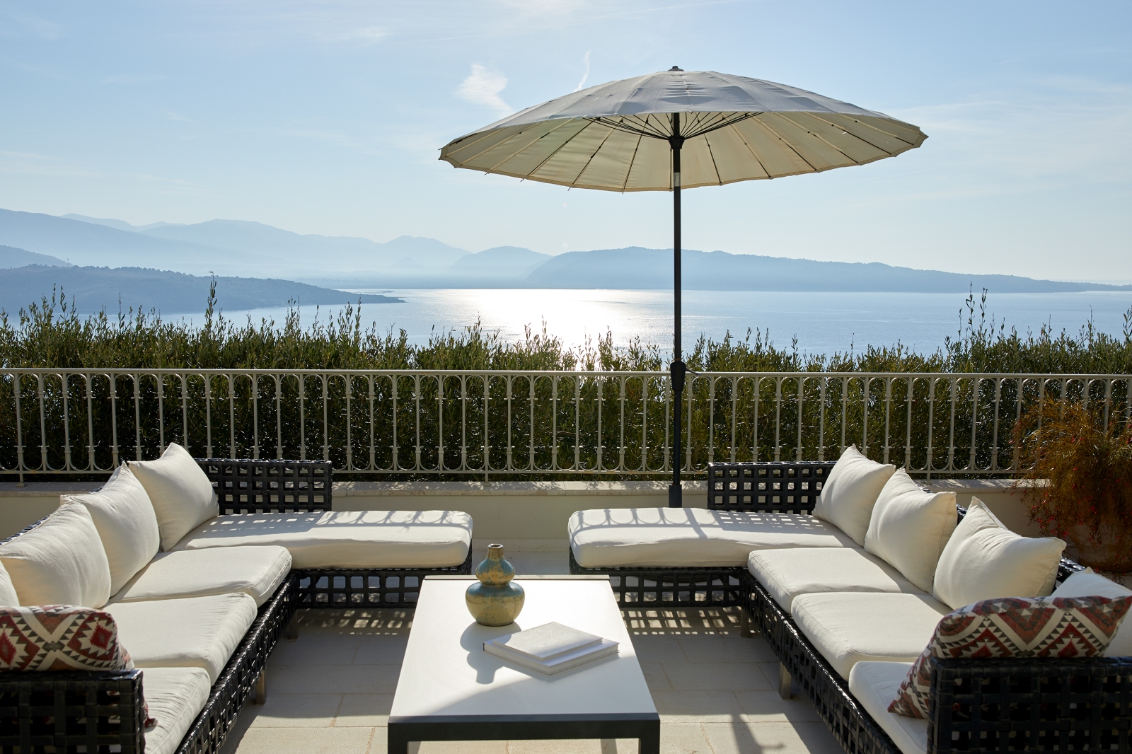 Terrace with wicker outdoor seating and parasol at Villa Kerasia in Corfu