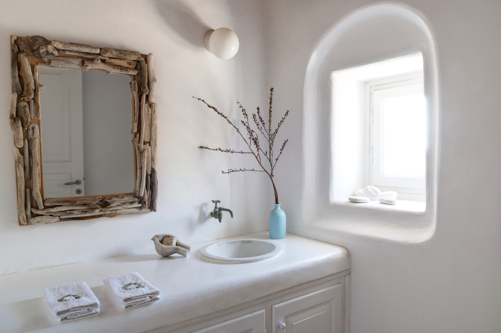 Bathroom with mirror, sink, towels, plant and windows at Villa Mari on Mykonos, Greece