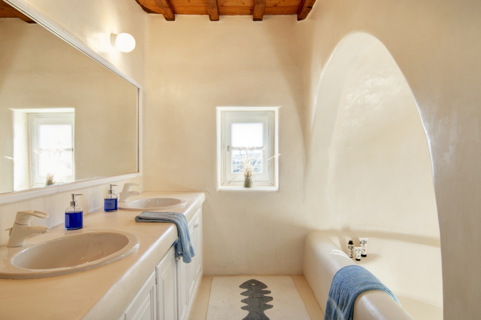 Bathroom with double sinks, large  mirror, bath, and window at Villa Mari on Mykonos, Greece
