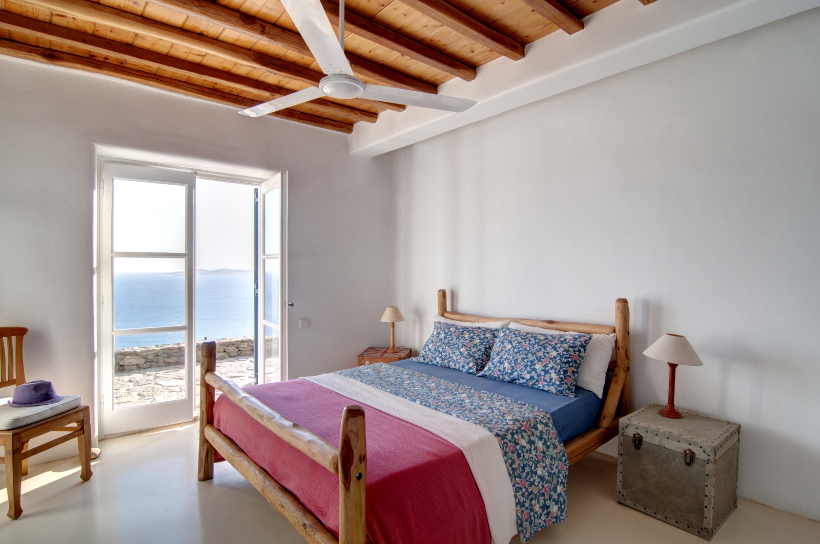 Bedroom with double bed, bedside tables, lamps, chair, ceiling fan and access to terrace at Villa Mari on Mykonos, Greece