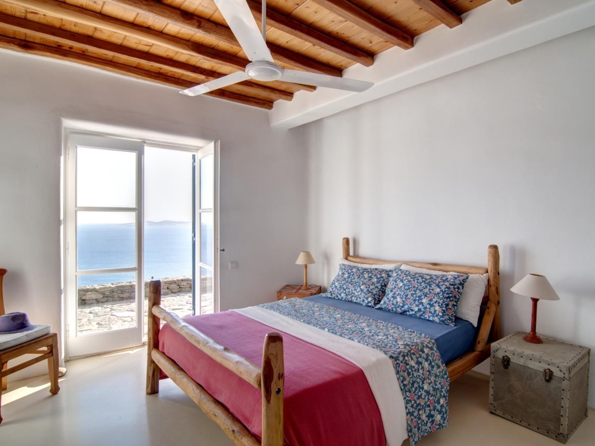 Bedroom with double bed, bedside tables, lamps, chair, ceiling fan and access to terrace at Villa Mari on Mykonos, Greece