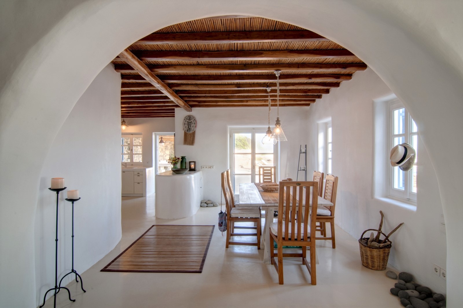 Dining room with candles, dining table, chairs, windows and hanging lights at Villa Mari on Mykonos, Greece