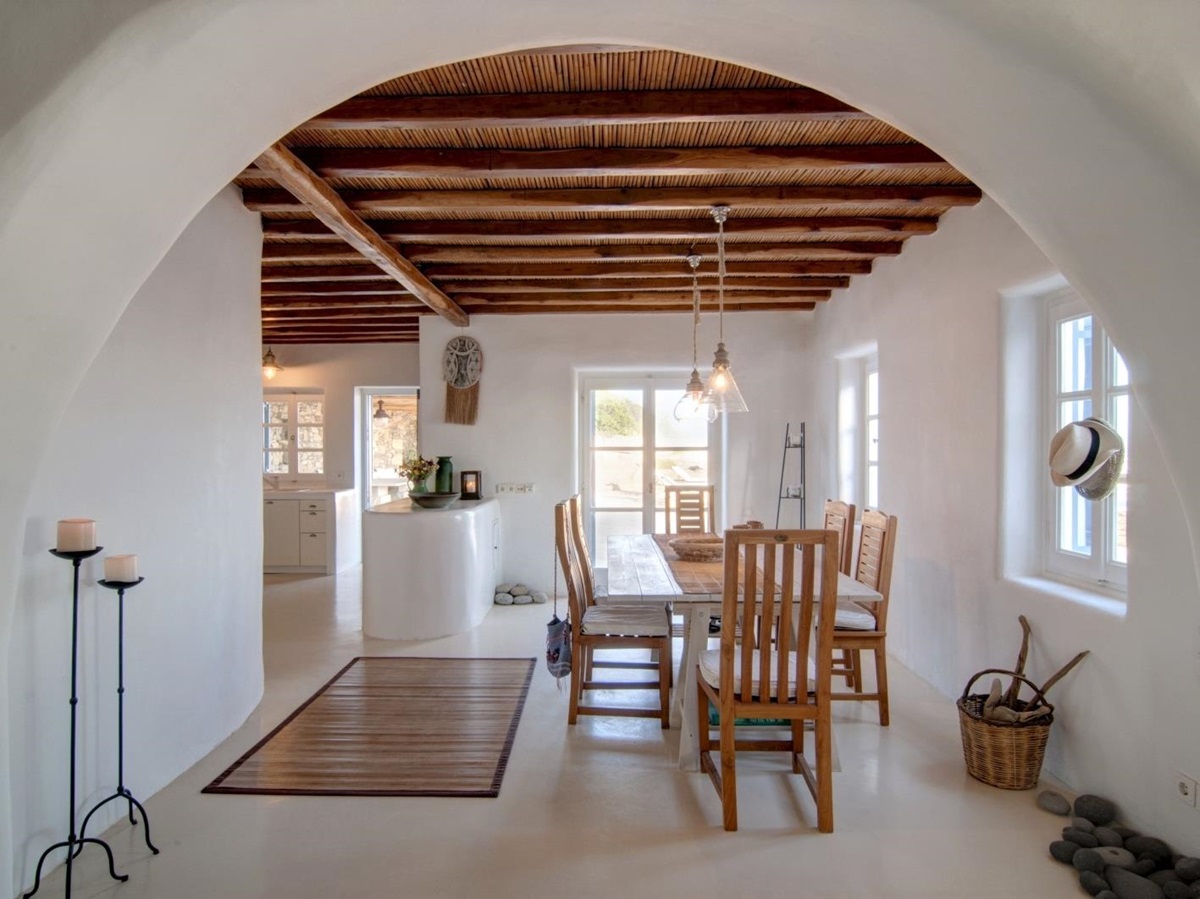 Dining room with candles, dining table, chairs, windows and hanging lights at Villa Mari on Mykonos, Greece
