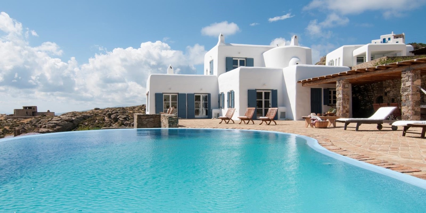 Façade of villa, infinity pool and terrace with sun loungers at Villa Mari on Mykonos, Greece