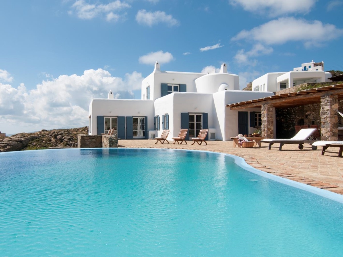 Façade of villa, infinity pool and terrace with sun loungers at Villa Mari on Mykonos, Greece
