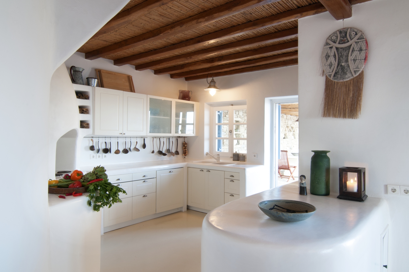 White kitchen with fresh food, appliances and bar at Villa Mari on Mykonos, Greece
