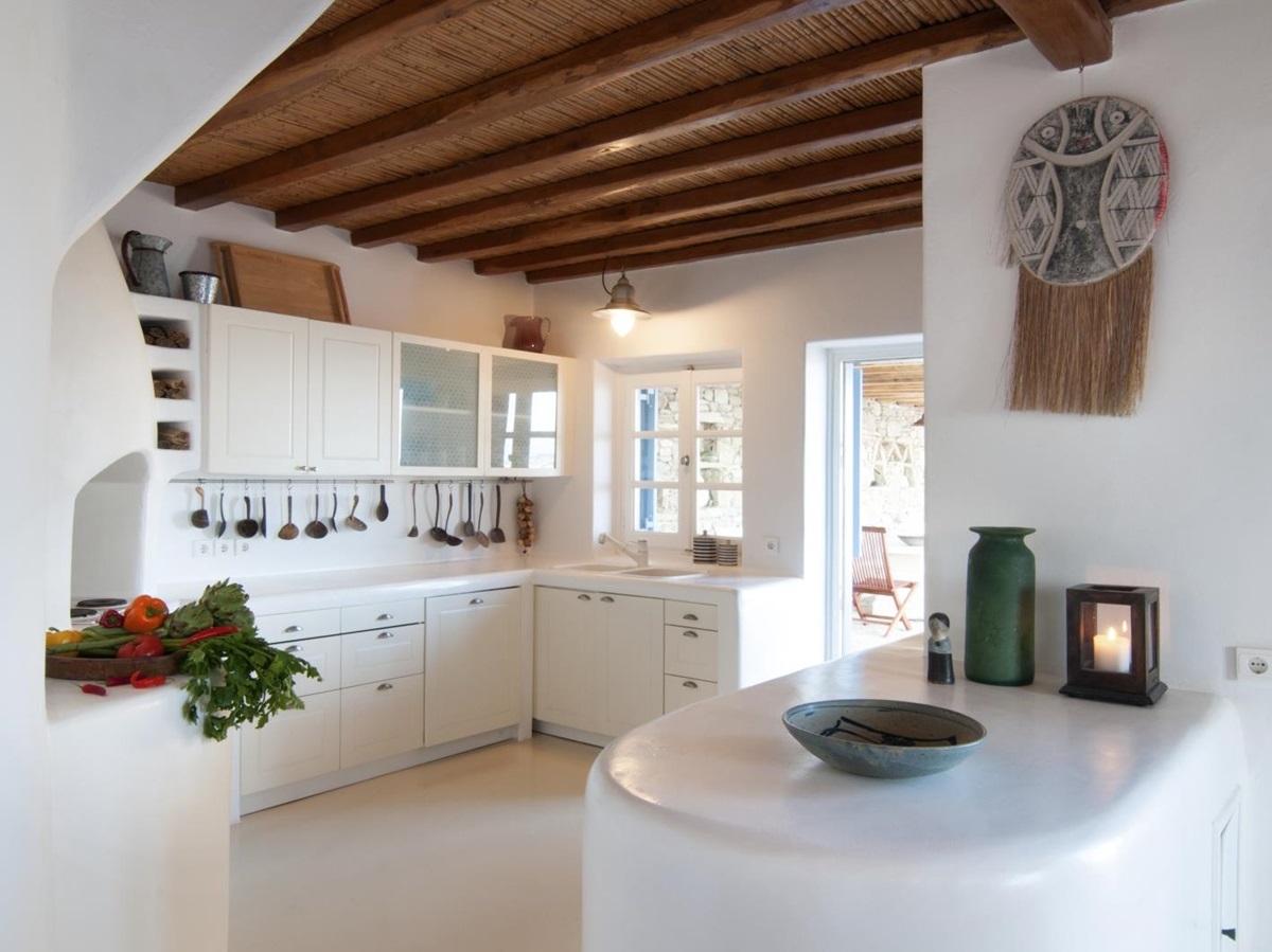 White kitchen with fresh food, appliances and bar at Villa Mari on Mykonos, Greece