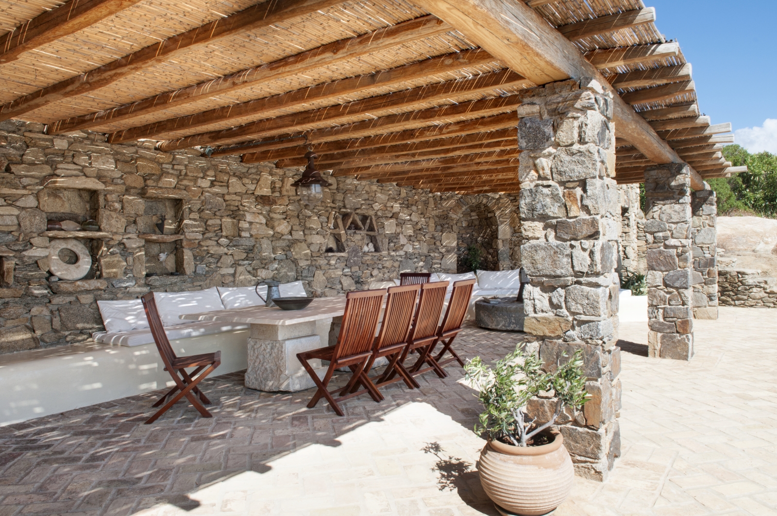 Covered outdoor dining area with table, chairs, and plants at Villa Mari on Mykonos, Greece