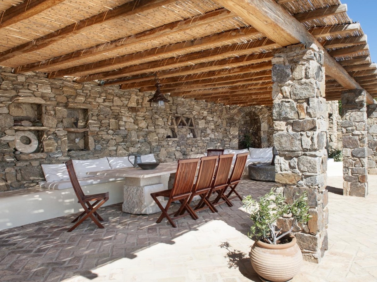 Covered outdoor dining area with table, chairs, and plants at Villa Mari on Mykonos, Greece