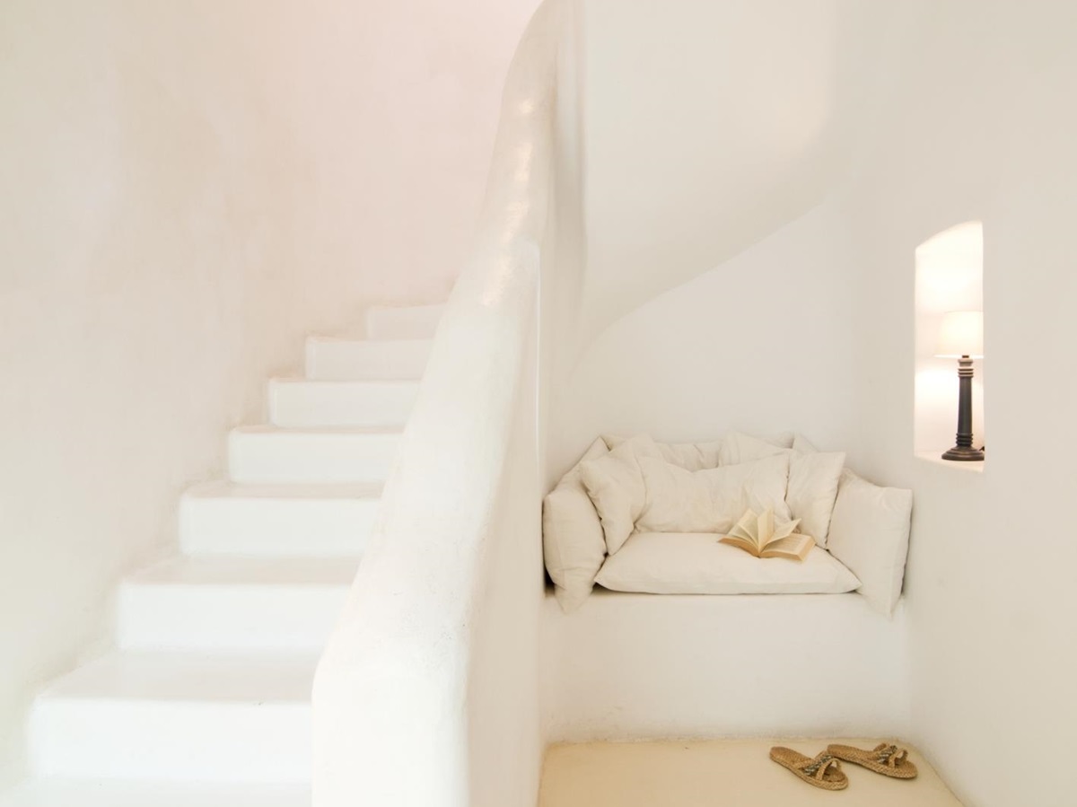 Reading corner next to staircase with cushions, book and candle at Villa Mari on Mykonos, Greece