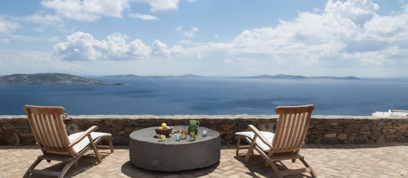 Terrace with sun loungers, table and sea view at Villa Mari on Mykonos, Greece
