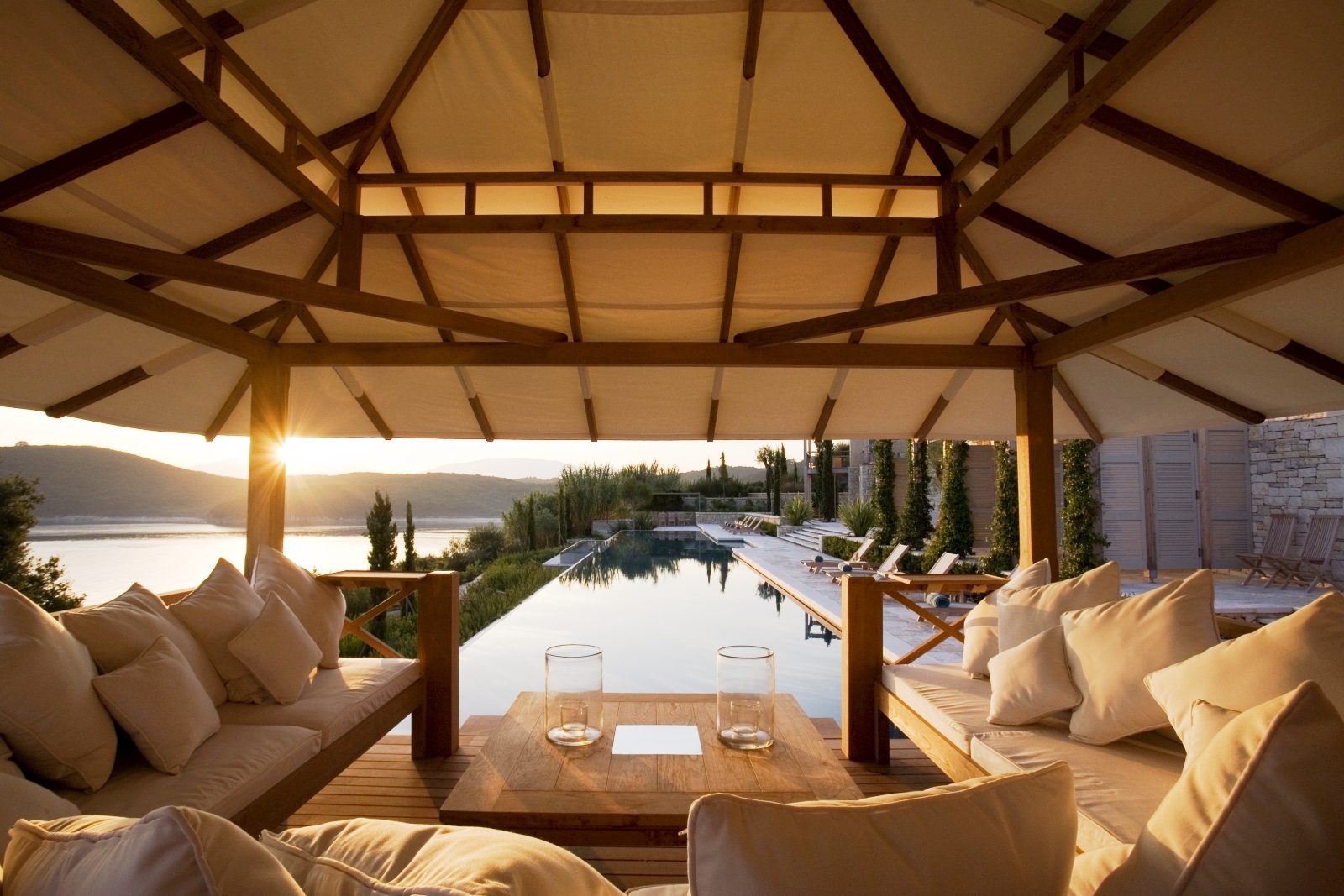 Lounge area by pool with sofas, coffee table and view of sea, sun loungers and patio at Villa Penelope on Corfu, Greece 