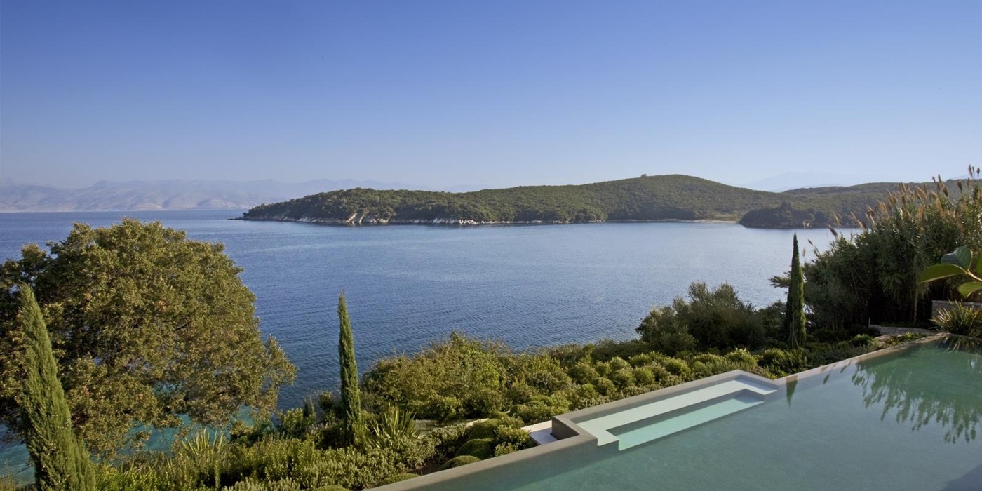 View of pool, trees, plants, sea and nearby headland at Villa Penelope on Corfu, Greece