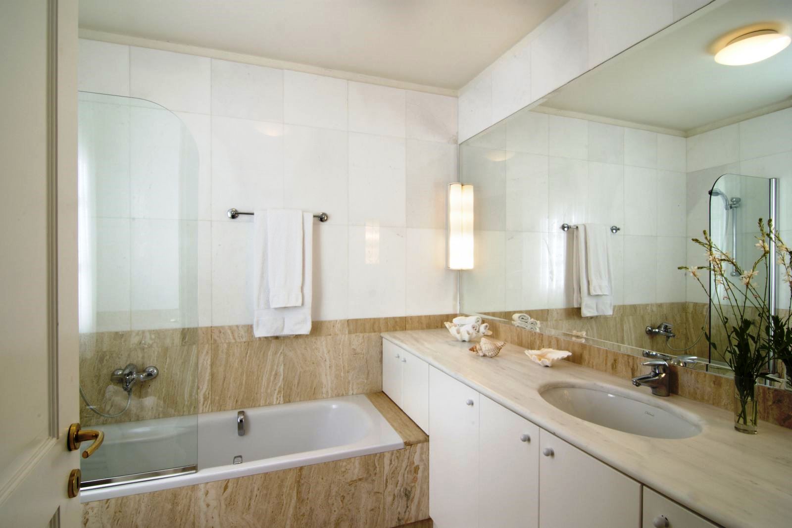 Cream coloured bathroom with bathtub and wall covered by a mirror behind the sink at Villa Selene in Crete