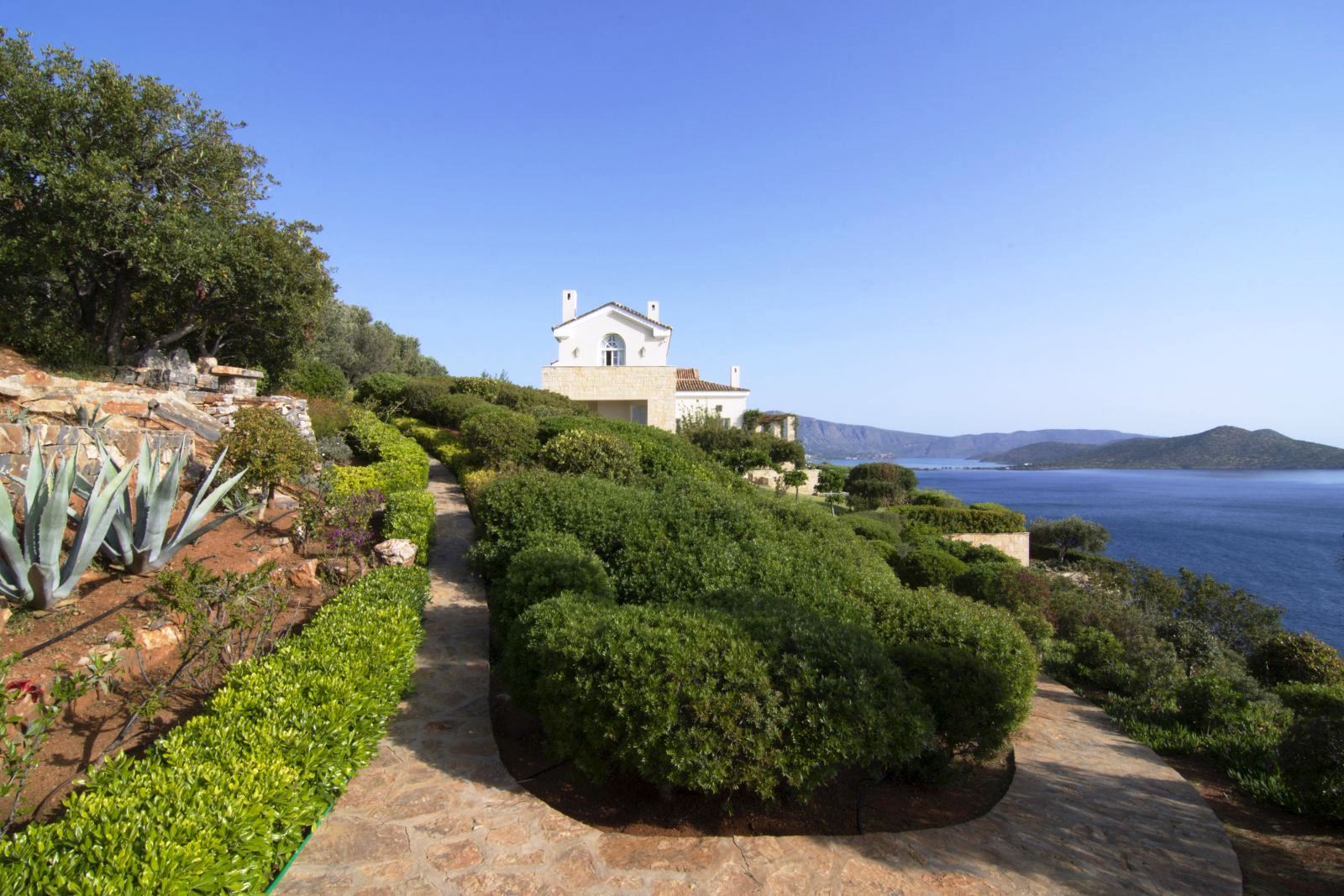 Gardens and paved paths leading to Villa Selene in Crete with views over the sea