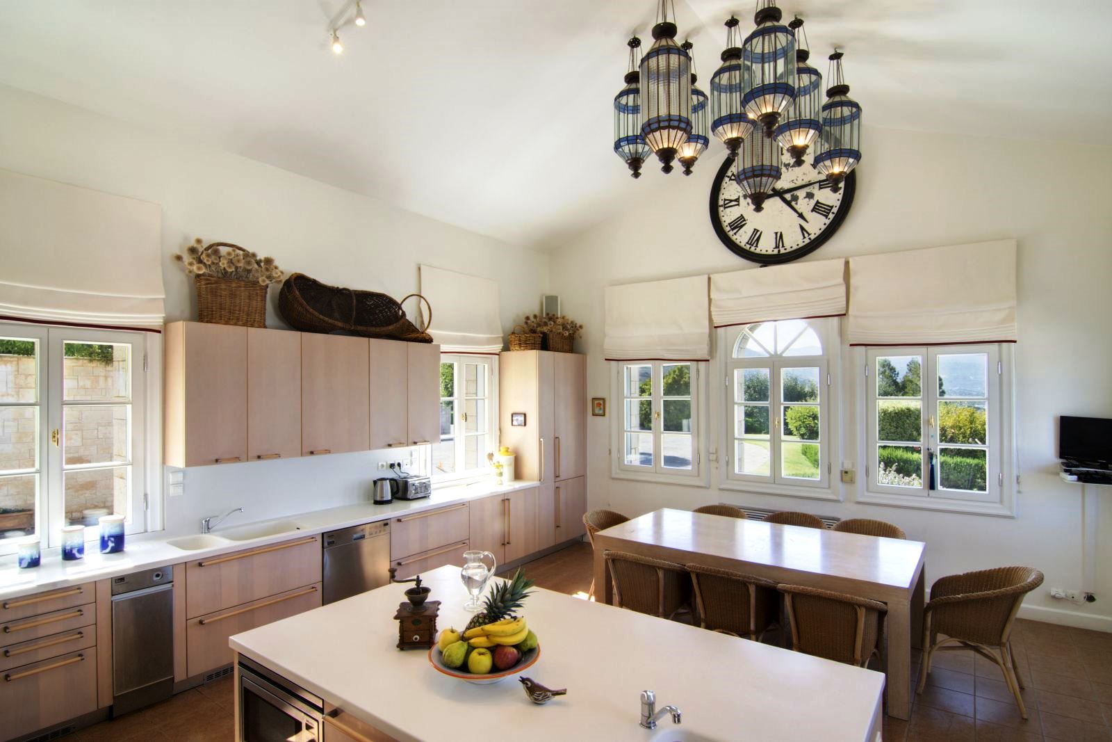 Cream coloured kitchen with dining area and windows overlooking the gardens at Villa Selene in Crete