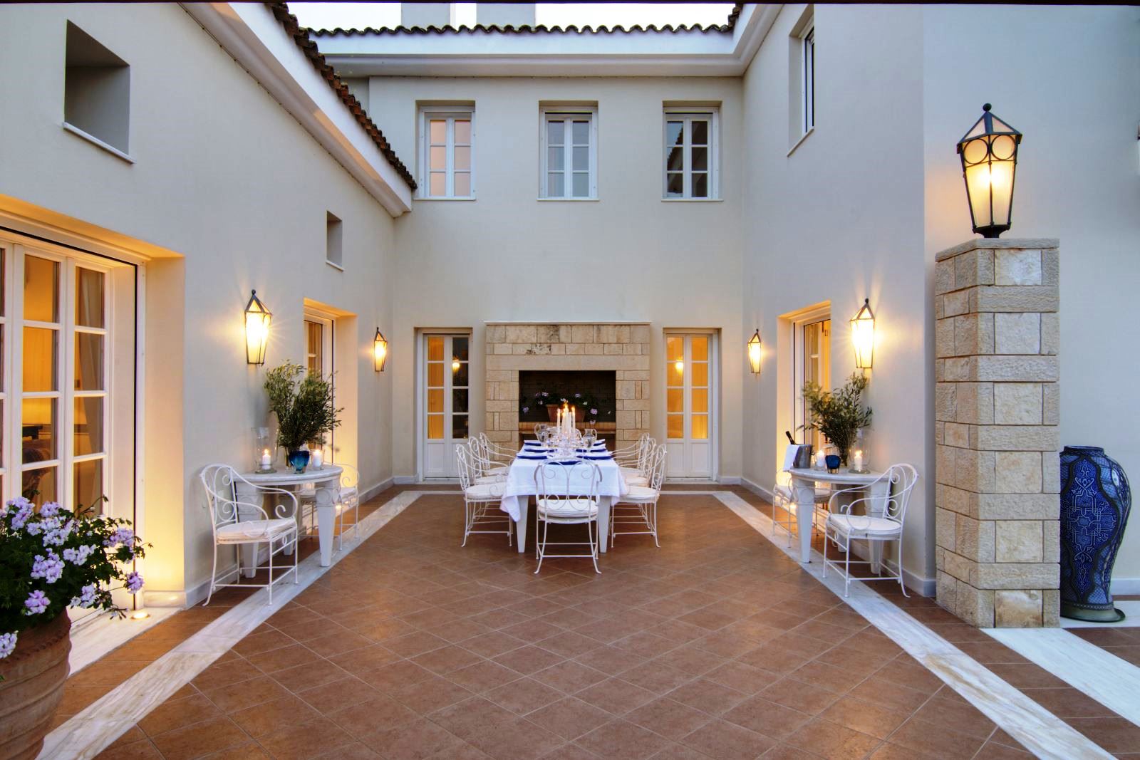 Outdoor dining area at Villa Selene in Crete with long table set for dinner with a white cloth and candles and white chairs at Villa Selene in Crete