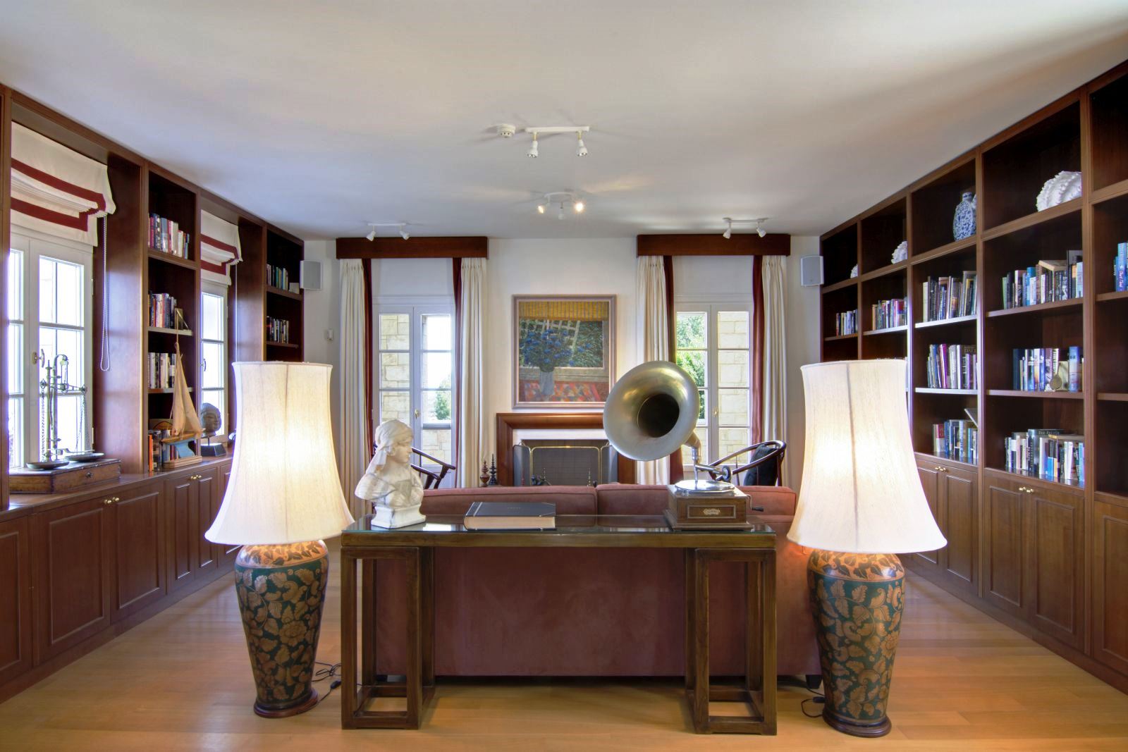 Study with floor to ceiling book shelves and brown sofa with two big lamps at either end at Villa Selene in Crete