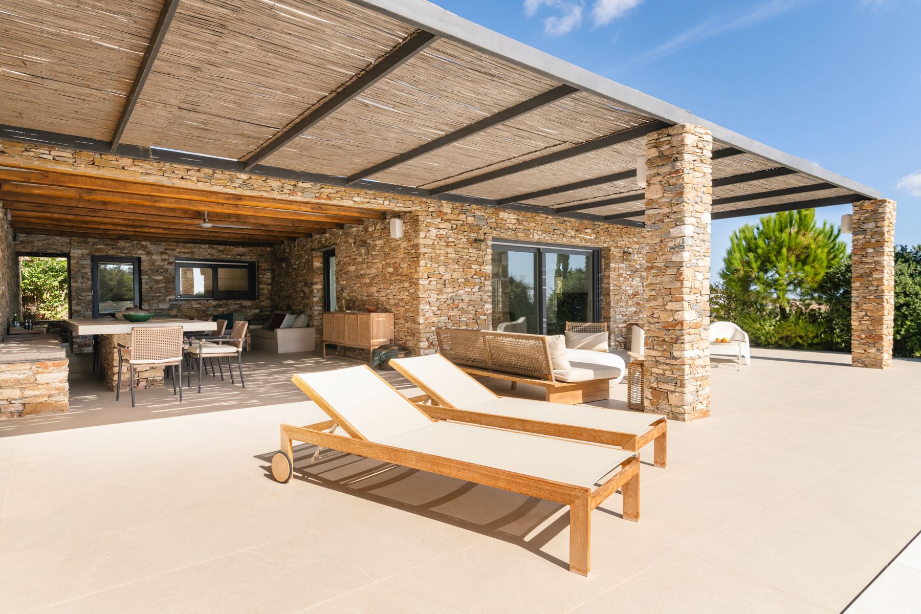 Covered terrace with seating and sun loungers at Villa Thalia, Sifnos