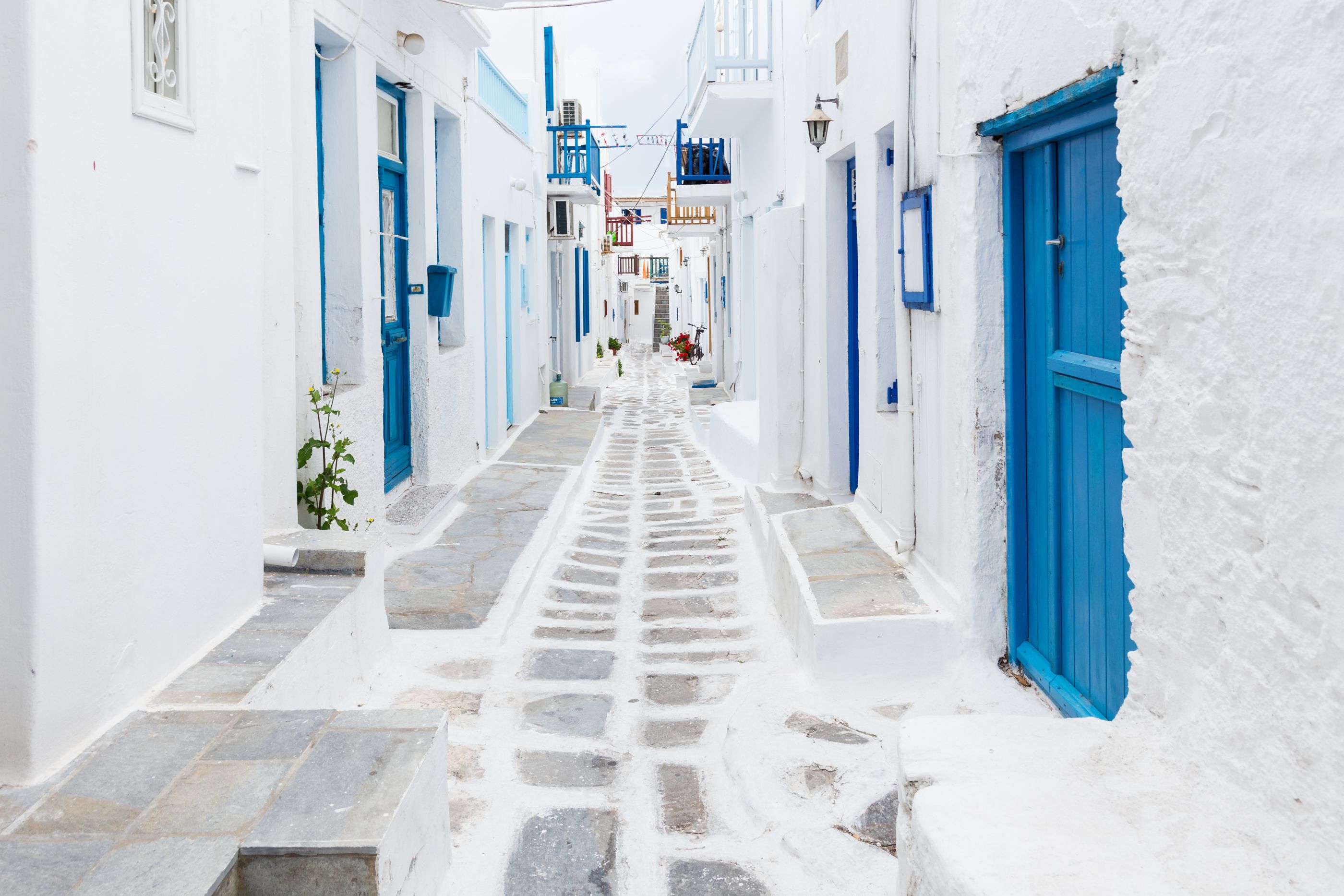 White street with blue doors in Mykonos, Greece