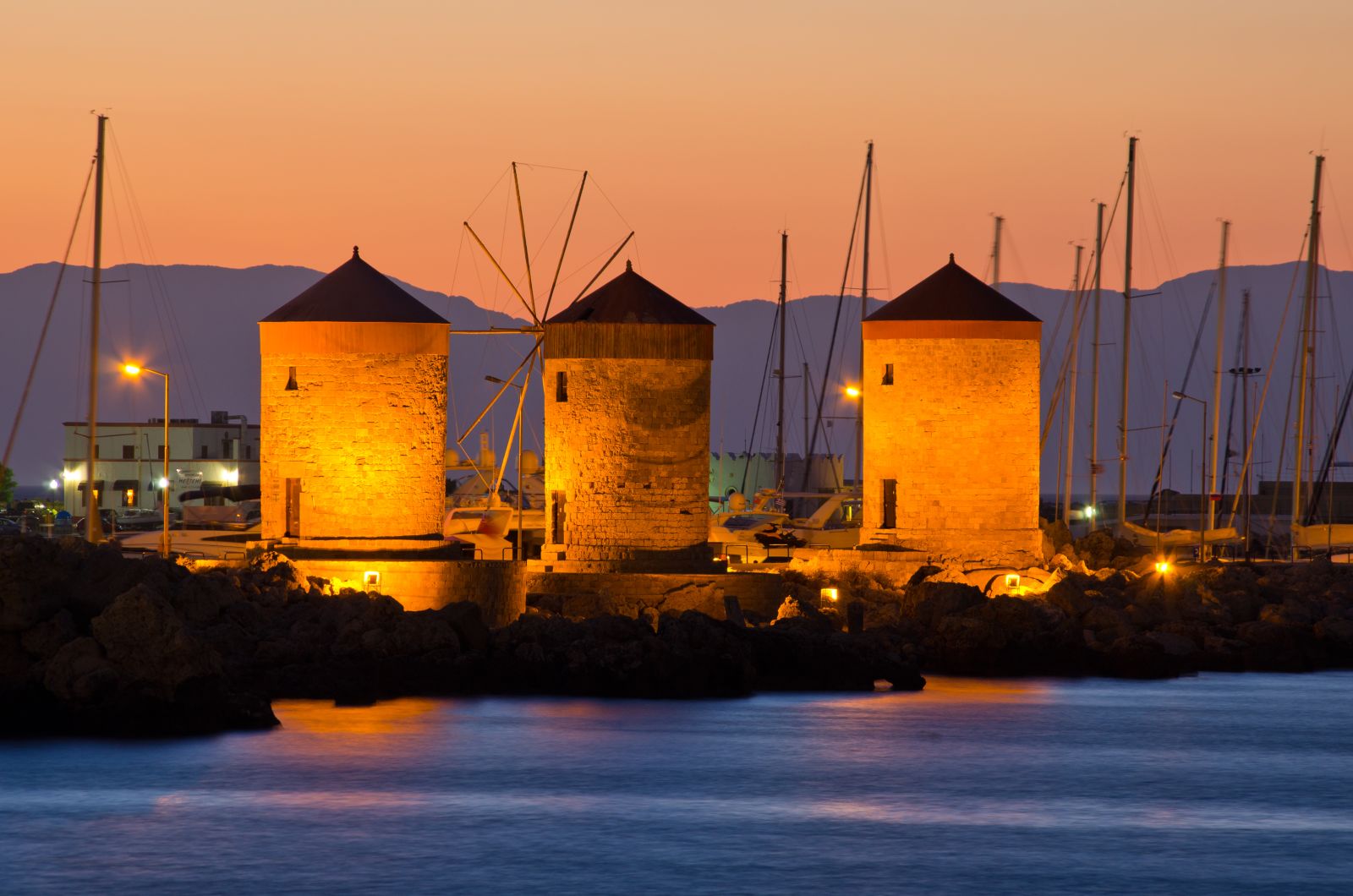 The windmills on the harbour at Rhodes illuminated at sunset