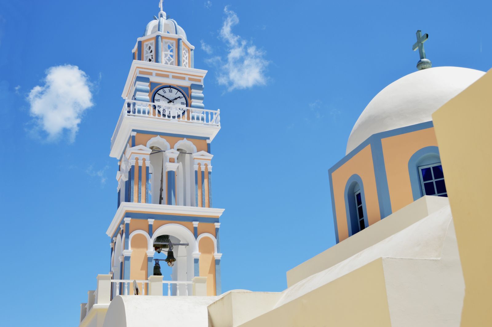 Pastel painted church spire and dome in Santorini, Greece