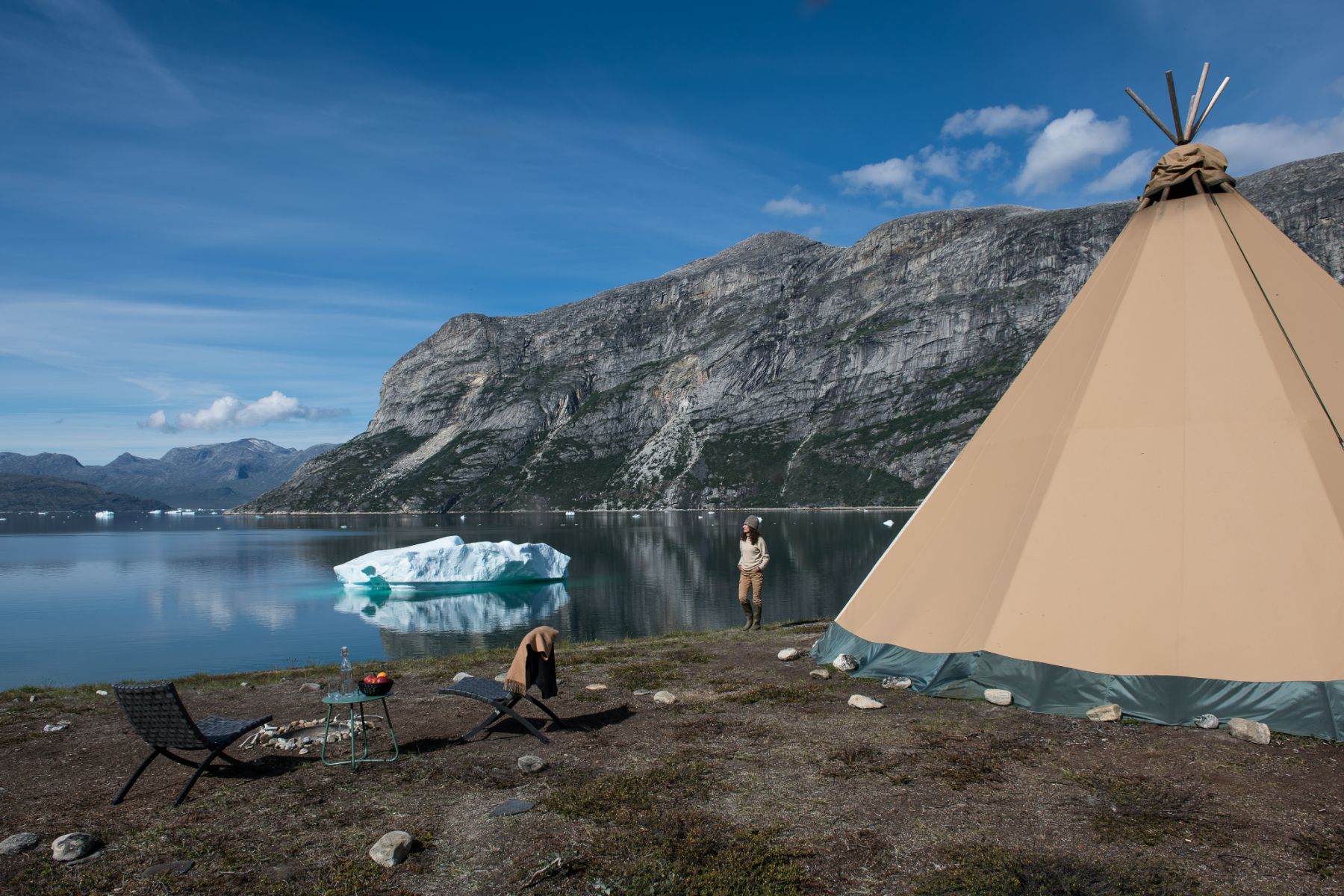 Lady looking at an iceberg near her tipi at Camp Kiattua Greenland