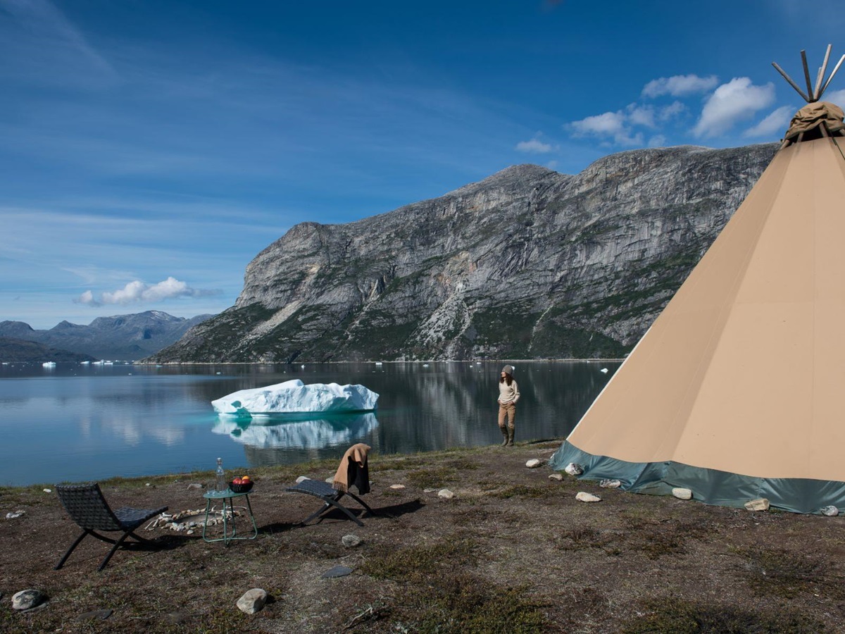 Lady looking at an iceberg near her tipi at Camp Kiattua Greenland